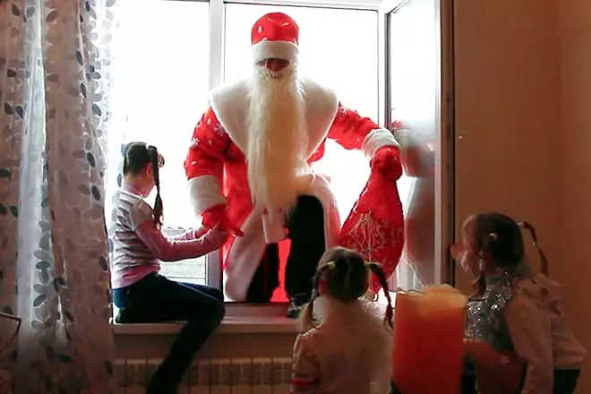 Santa Claus kāpās logā